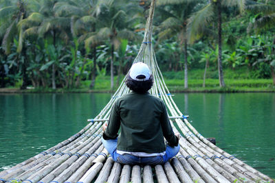 Rear view of man sitting on riverbank