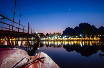 Boats moored in illuminated city against sky at night