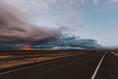 Empty road against cloudy sky