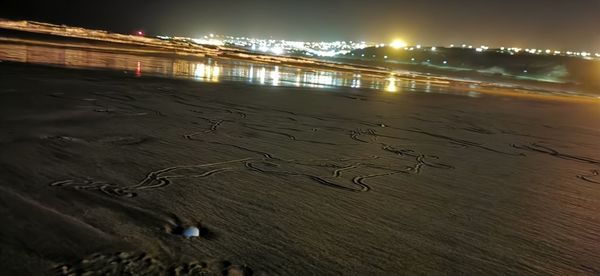 High angle view of illuminated beach against sky at night