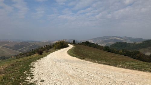 Road leading towards mountains against sky