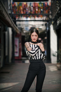 Portrait of woman standing against building in city