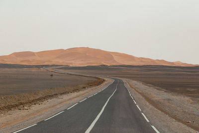 Empty road in desert against clear sky