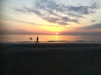 Silhouette people on beach against sky during sunset