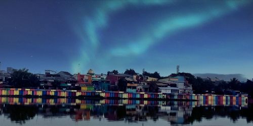 Buildings by lake against sky in city