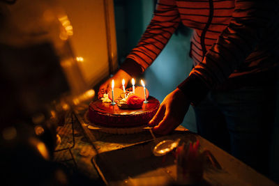 Midsection of woman with candles on birthday cake