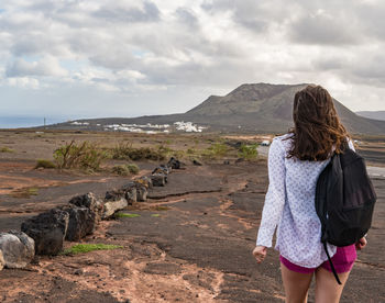 Rear view of woman standing on mountain against sky