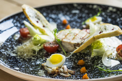 Close-up of chicken caesar salad with poached eggs served in plate on table