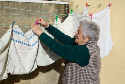 Side view of woman drying cloth on clothesline