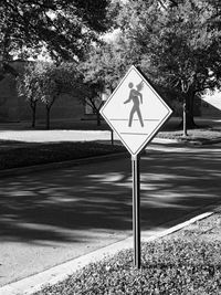 Road sign by street during sunny day