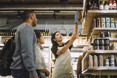 Saleswoman holding canned product to customers at store