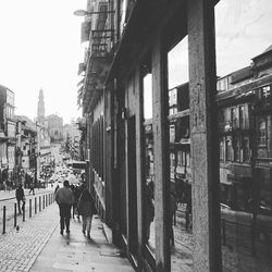 Rear view of people walking on street amidst buildings in city