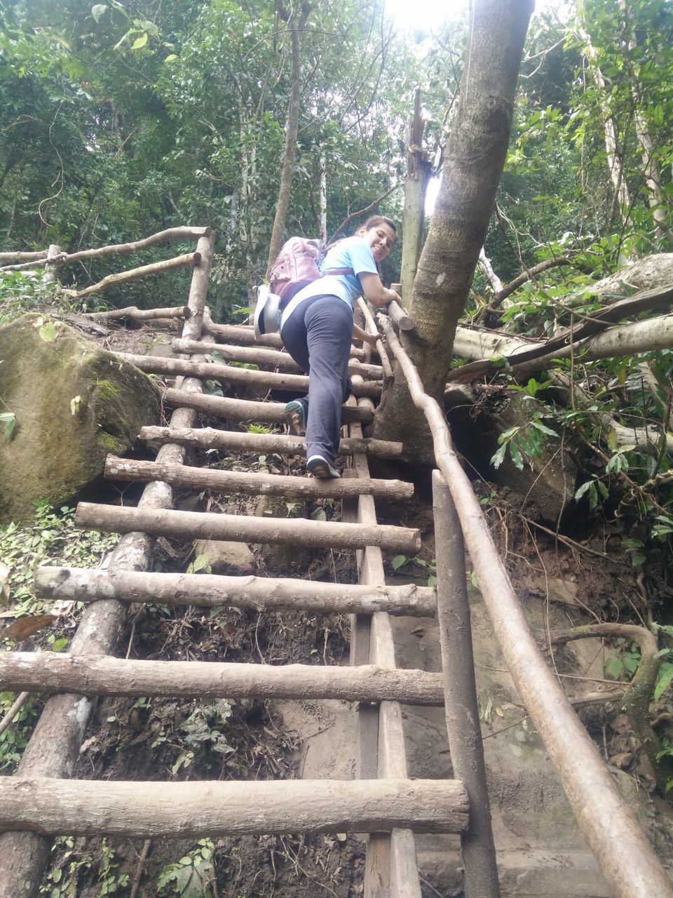 LOW ANGLE VIEW OF MAN ON STAIRCASE AT FOREST