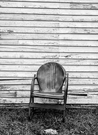 Empty wooden bench in front of wall