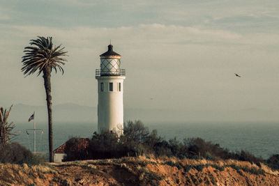 Lighthouse by sea against sky