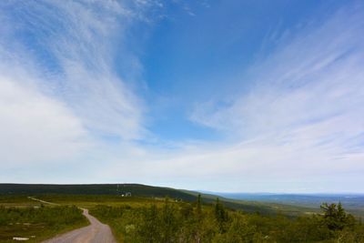 Scenic view of road amidst landscape against blue sky