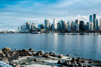 Sea by city buildings against sky