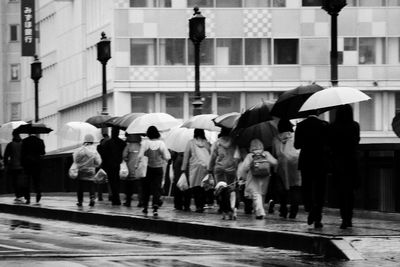 Rear view of people walking on bridge during rainy season