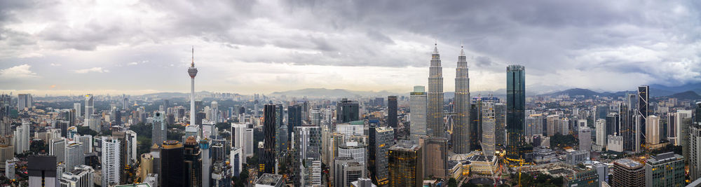 Panoramic view of city buildings against cloudy sky
