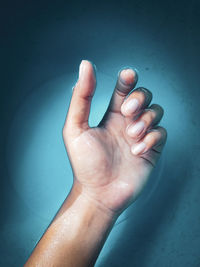 Close-up of human hand against blue wall