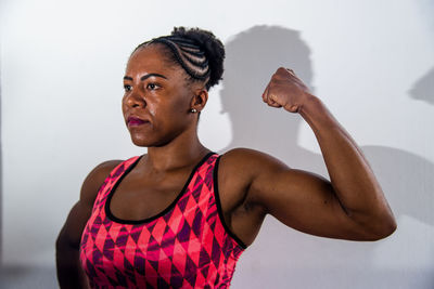 Side view of young woman exercising against black background