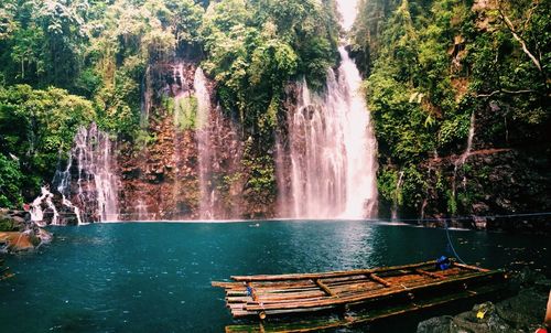 Wooden raft on river against tinago falls