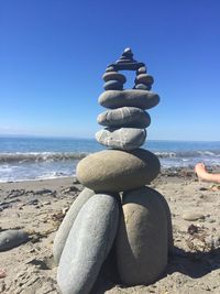 Stack of pebbles on beach against clear blue sky