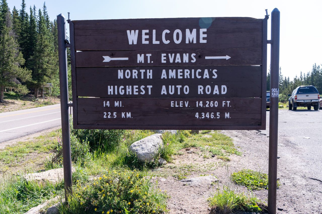 INFORMATION SIGN ON ROAD BY TREES