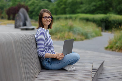 Female blogger in a public place works on a laptop or creates audio content for her subscribers