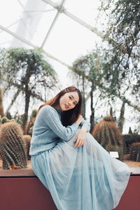 Young woman smiling while standing against trees