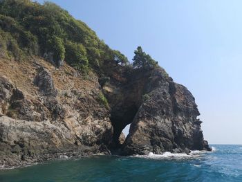 Rock formations by sea against clear blue sky