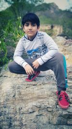 Portrait of boy crouching on rock
