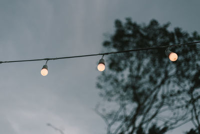 Low angle view of illuminated light bulb against sky