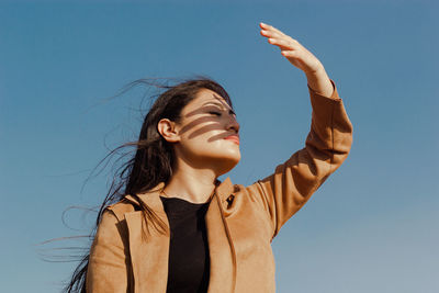 Low angle view of young woman standing against clear sky