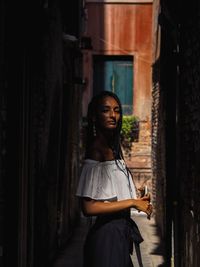 Side view of young woman standing in alley