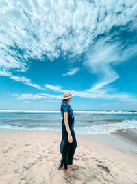Woman standing at beach against sky