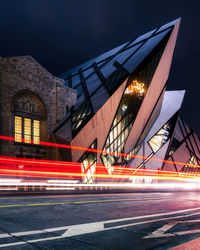 Light trails on bridge by buildings in city at night