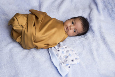 Portrait of cute baby lying on bed at home