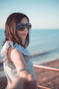 Portrait of young woman wearing sunglasses against sea