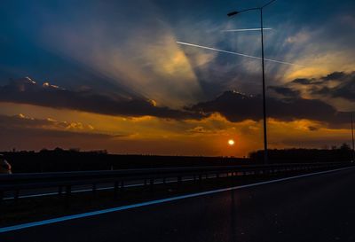 Silhouette road against sky during sunset