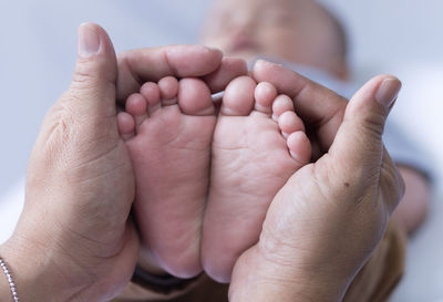 Cropped hands of parent holding baby barefoot