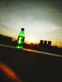 Close-up of glass bottle against sunset sky