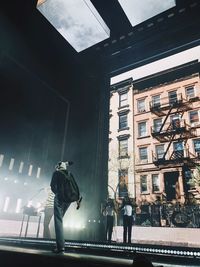 Low angle view of man standing on street by building