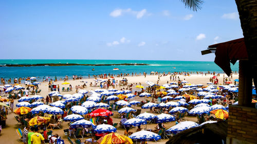 Group of people on beach by sea against sky