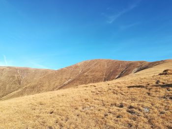 Scenic view of arid landscape against blue sky