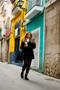 Young woman sends a message on her phone while walking down the street