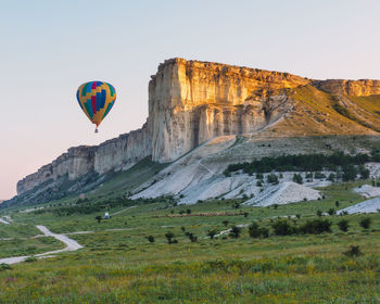 Hot air balloon flying over mountains against clear sky