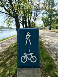 Close-up of information sign on road by tree