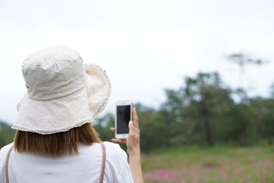 Rear view of woman using mobile phone on field