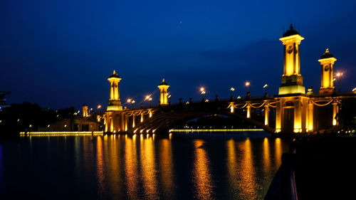 Illuminated bridge over river at night